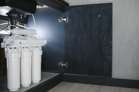 Three-stage water filter with three vertical housings installed inside an under-sink cabinet