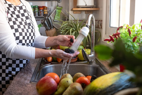 Washing blackberries and other fruits with filtered water from a kitchen faucet, ensuring food safety by removing arsenic.