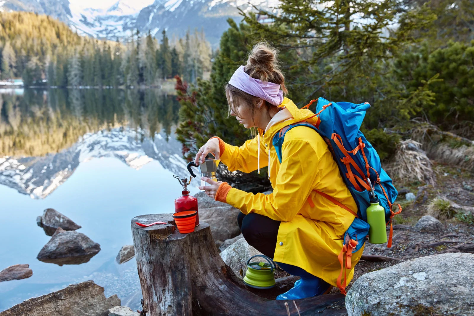 A female backpacker filtering lake water at a mountain campsite for safe outdoor drinking and hydration.