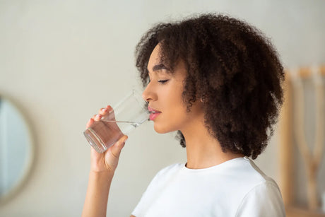 Woman drinking clean water, free of rotten egg odor after using sulfur water filter