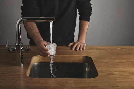  Person fills a glass with pure water filtered by reverse osmosis technology that effectively eliminates arsenic and other harmful water contaminants.