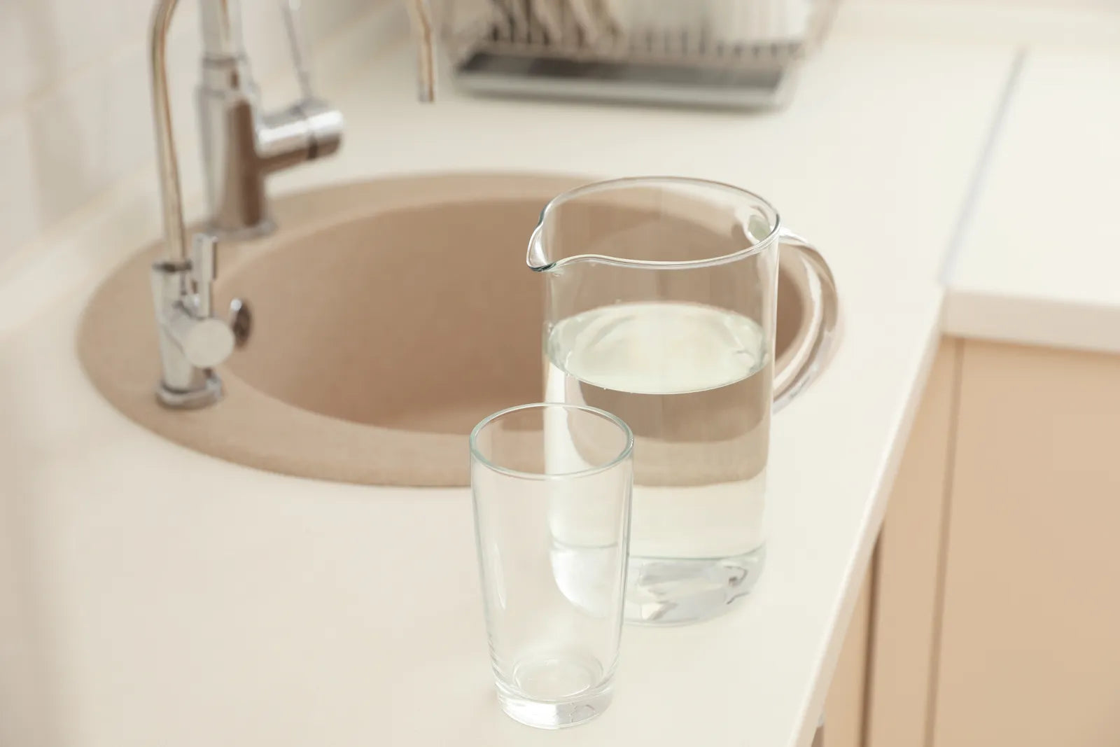 Glass of pure filtered water next to a kitchen sink, representing the clean water output from a properly installed RO system.