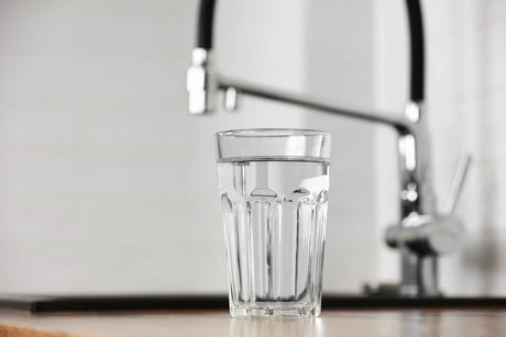 A clear glass of drinking water on a kitchen counter, highlighting home hydration and clean living.