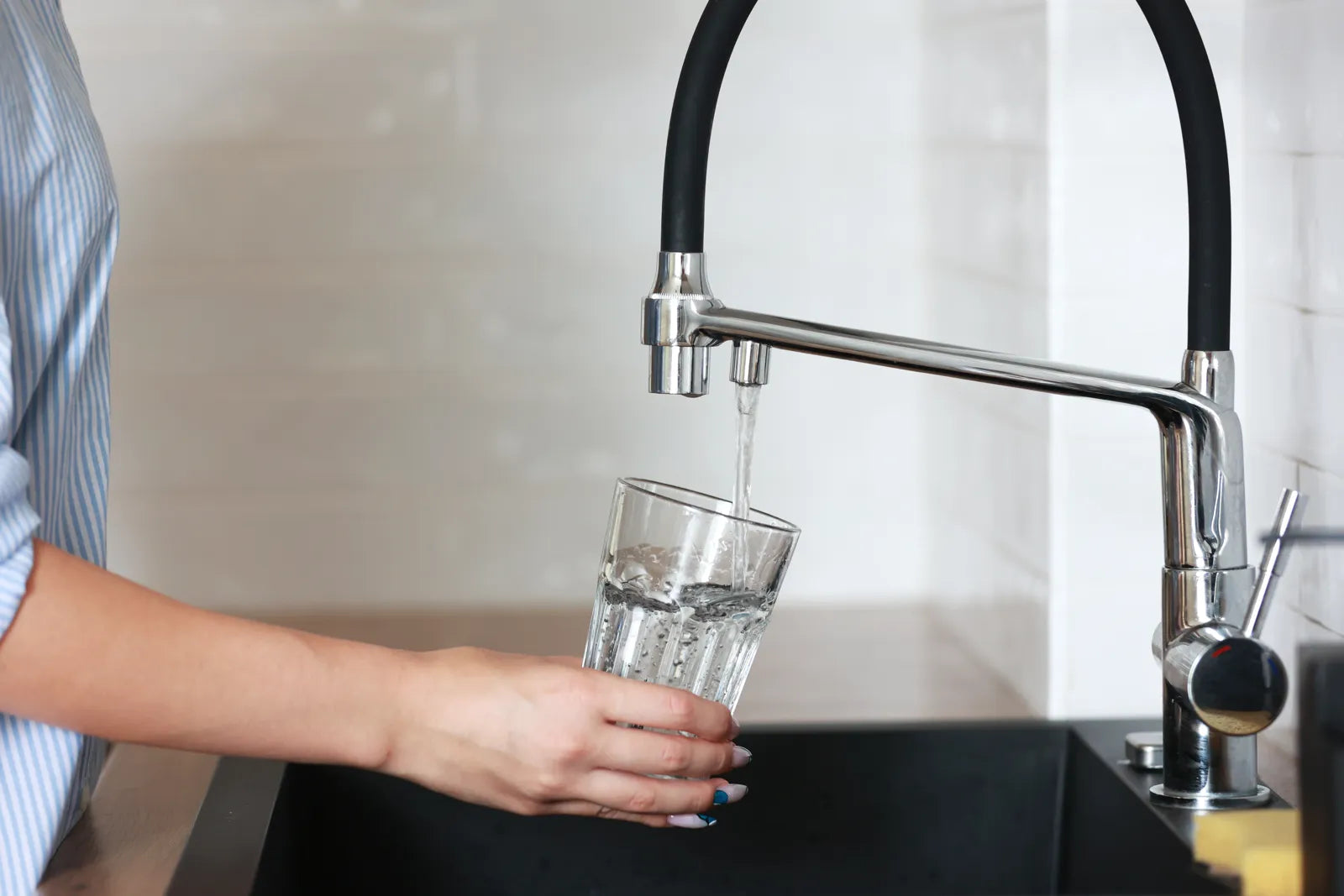 Person filling glass with clean filtered water from RO faucet, enjoying long-lasting purified water from a well-maintained reverse osmosis membrane.