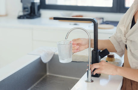 A person pours water filtered by a taste water filter into a glass.