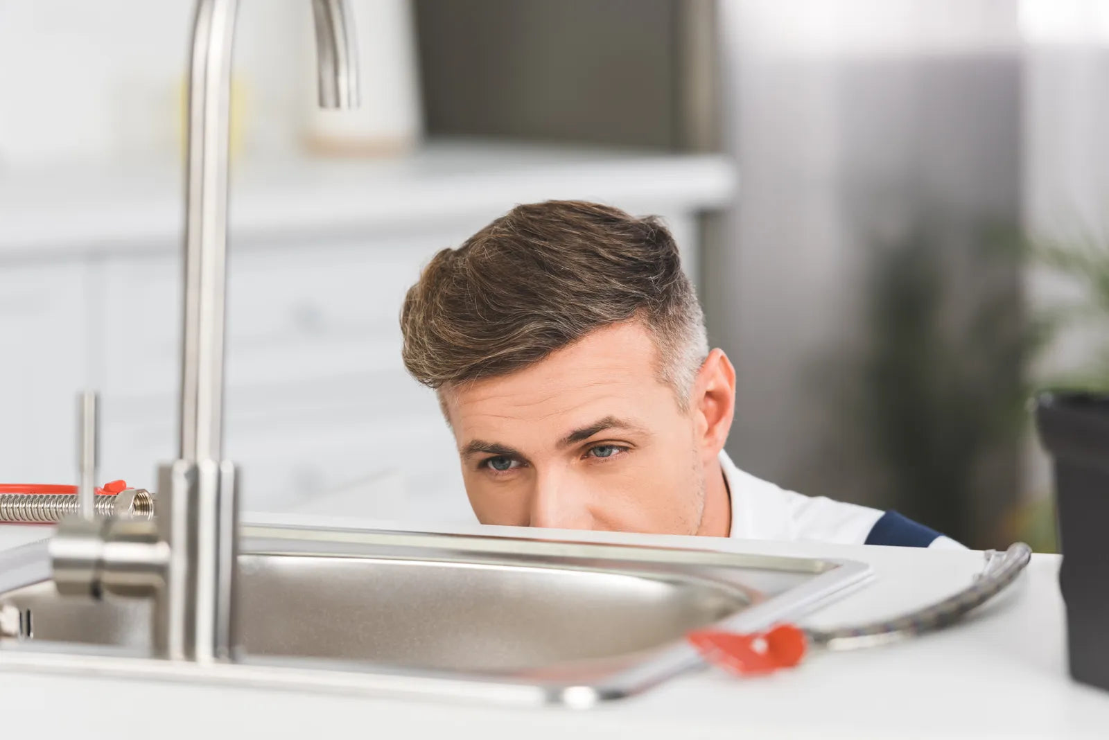 Professional plumber inspecting under-sink area to diagnose water filter noise issues