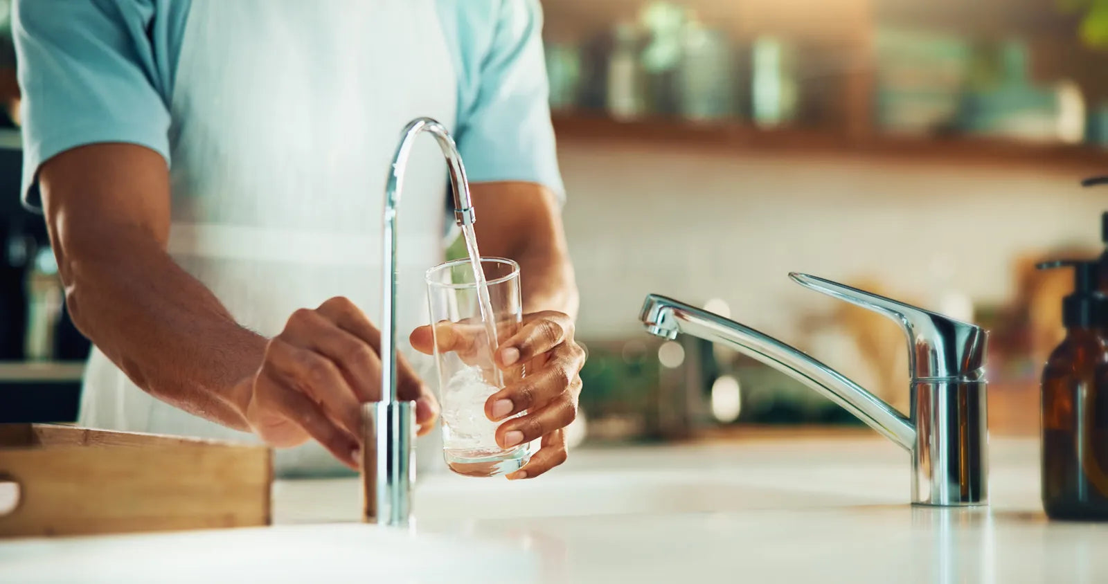 A person fills a glass with reverse osmosis water, which has a low pH.