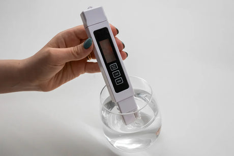 A person uses a TDS meter to test the total dissolved solids in drinking water.