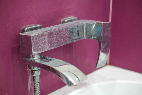 Modern square chrome faucet covered with white limescale and water stains, showing wear and mineral buildup.