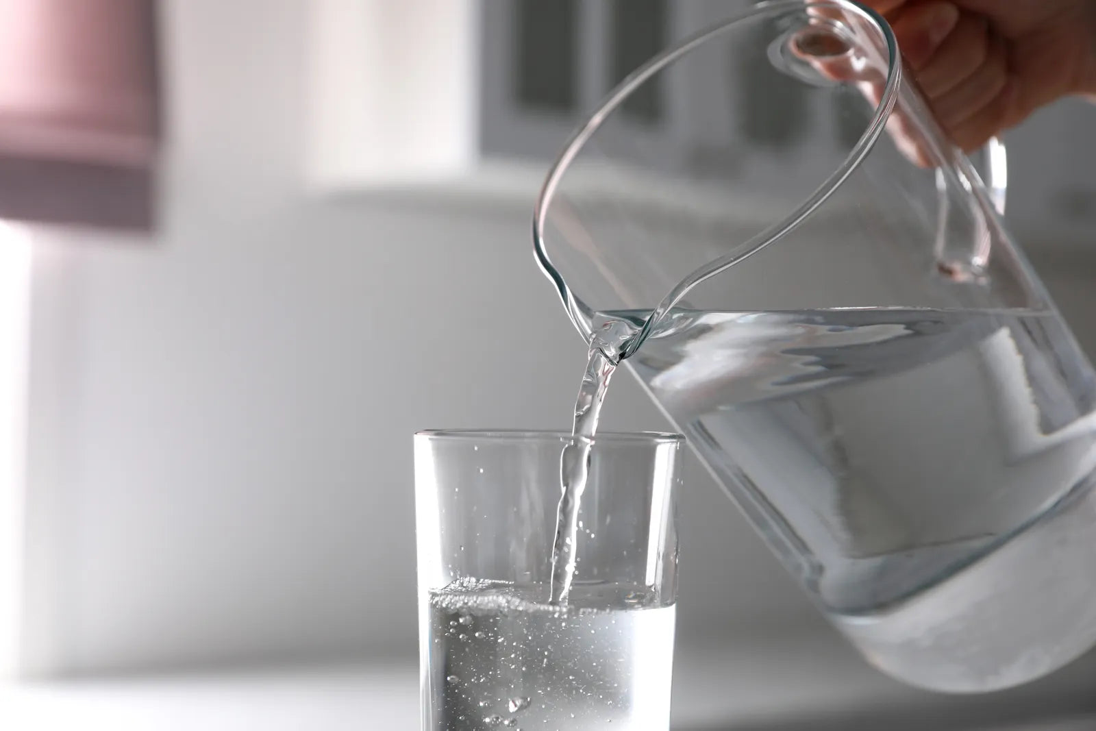 Pouring water from a pitcher highlights the risks of drinking distilled water long-term.